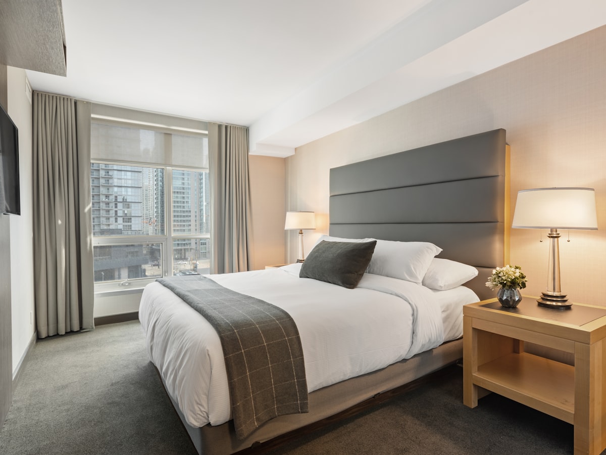 Frisch gereinigtes Hotelzimmer mit bezogenem Bett und Blick auf die Stadt