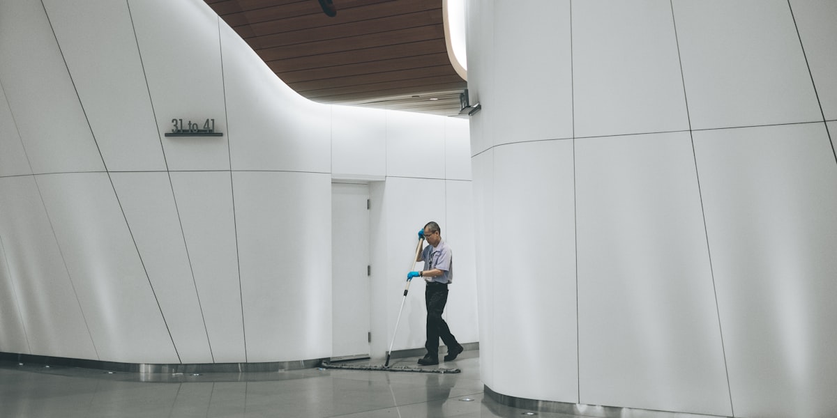 Reinigungskraft wischt den Boden in der hellen Lobby eines Gebäudes