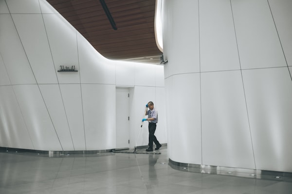 Reinigungskraft wischt den Boden in der hellen Lobby eines Gebäudes