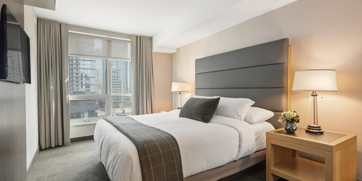 Frisch bezogenes Hotelzimmer mit weißer Bettwäsche und Nachttischlampe